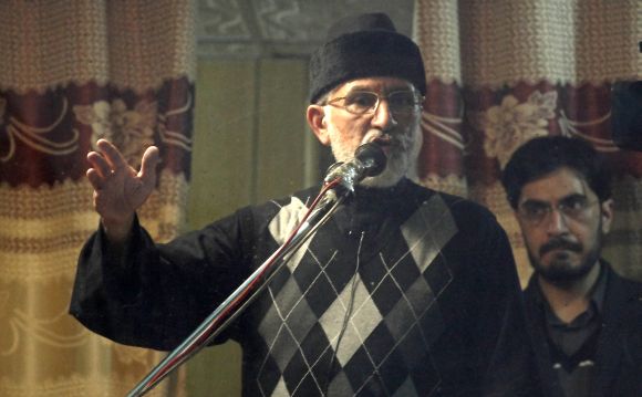 Dr Tahir-ul Qadri addresses his supporters behind the window of an armoured vehicle in Islamabad