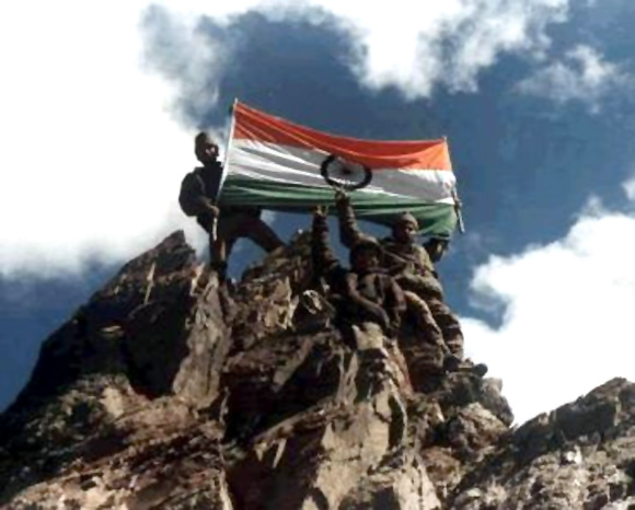 Indian soldiers hoist the tricolour atop a recaptured peak during the Kargil war.