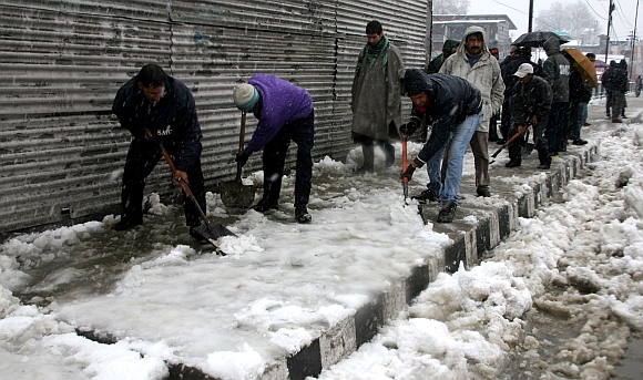 Workers clear footpaths after the heavy snowfall
