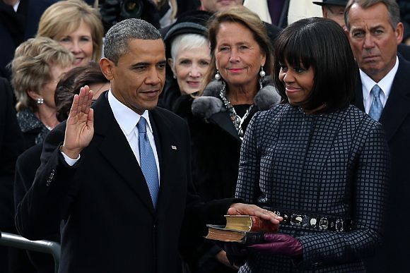 US President Barack Obama is sworn in during the public ceremony as First lady Michelle Obama looks on during the presidential inauguration on the West Front of the US Capitol January 21 in Washington, DC
