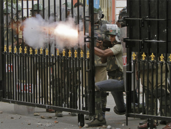 Riot police personnel fire tear gas towards pro-Telangana supporters