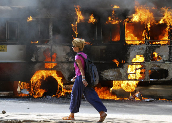 A foreign student of Osmania University walks past a bus set ablaze by pro-Telangana supporters