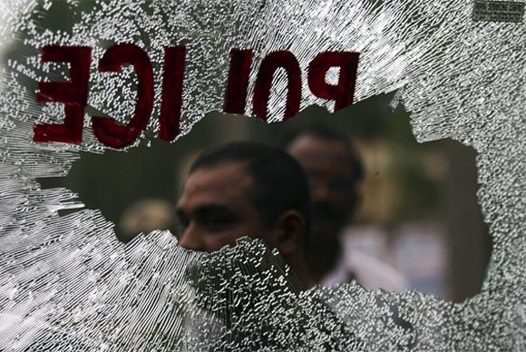 Onlookers are seen through the broken windowpane of a police vehicle damaged by pro-Telangana supporters