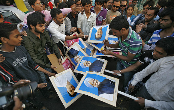 Demonstrators prepare to burn portraits of India's PM Singh and lawmaker Rahul Gandhi during a protest in Ahmedabad