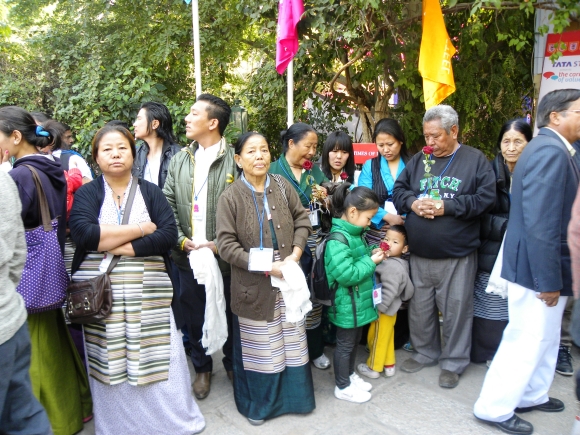 People wait for the Dalai Lama with roses