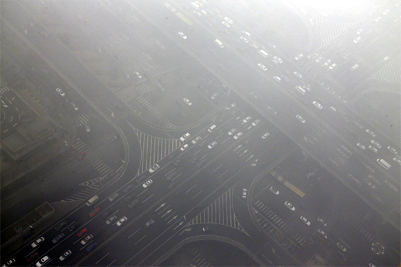 Cars drive through Guomao bridge on a hazy day in Beijing's central business district