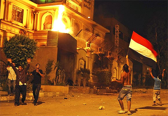 Protesters opposing Mursi wave Egyptian flag and shout slogans against him and members of the Muslim Brotherhood after attacking the national headquarters of the Muslim Brotherhood with Molotov cocktails in Cairo