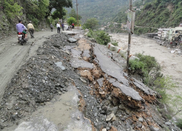  People walk along road that was damaged due to the floods in Uttarakhand 