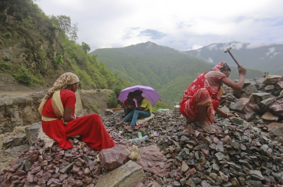 Workers repair a road damaged by a landslide, which was caused by heavy rainfall in Chamba, Uttarakhand