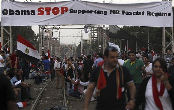 Protesters opposing Egyptian President Mohamed Mursi walk under a banner during a protest in front of the El-Thadiya presidential palace in Cairo