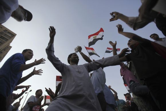 Protesters, who are against Morsi, dance and react in front of the Republican Guard headquarters in Cairo