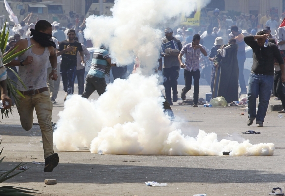Protesters who support Morsi react to tear gas fired by riot police during clashes outside the Republican Guard building in Cairo