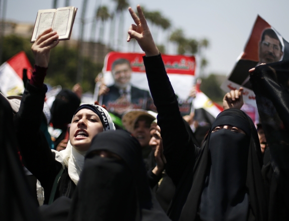 A protester, who supports former Egyptian President Mohamed Mursi, holds up a copy of the Koran as she and others march near Cairo University after Friday prayers in Cairo 