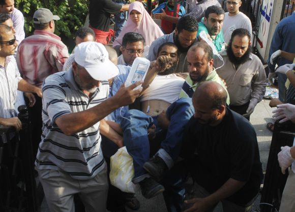 Supporters of Mohamed Mursi help a wounded supporter outside the Republican Guard headquarters in Cairo.