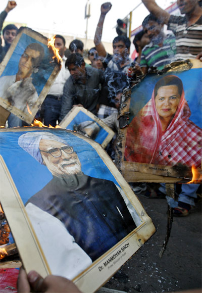Demonstrators burn portraits of Prime Minister Manmohan Singh, Congress President Sonia Gandhi and vice president Rahul Gandhi