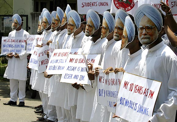 -Demonstrators wearing masks of India's Prime Minister Manmohan Singh hold placards during a protest