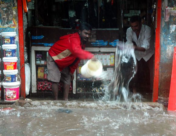 Shopkeers pour out buckets of rain water that entered a store in Sion on Friday