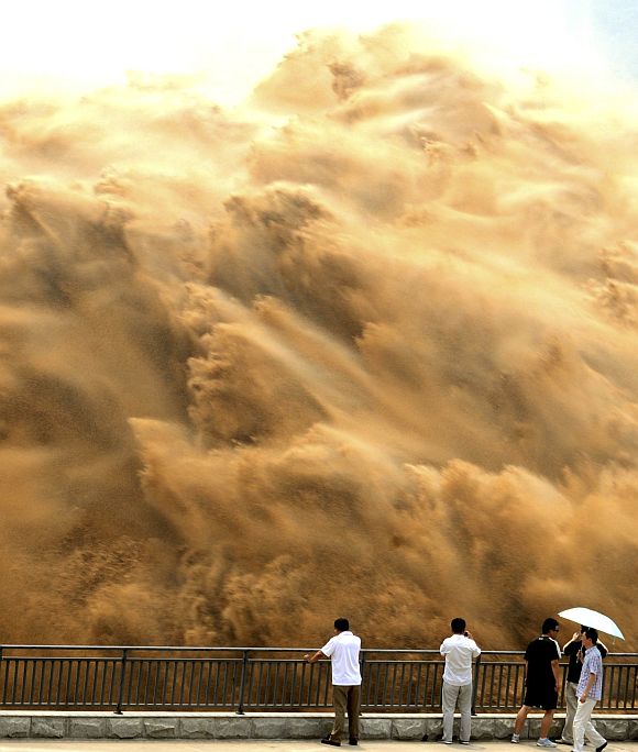 Visitors watch water gushing from the section of the Xiaolangdi Reservoir on the Yellow River