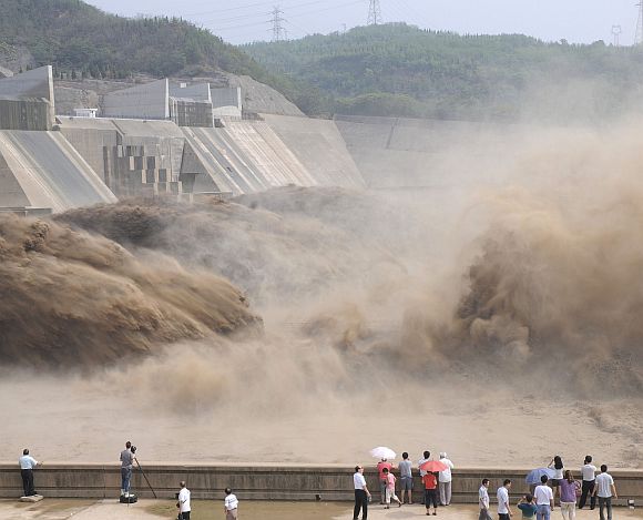 Visitors look at water gushing from the section of the Xiaolangdi Reservoir on the Yellow River