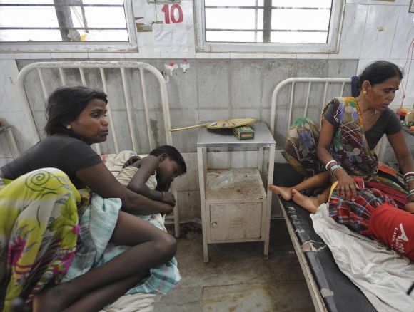 Women sit next to their children, who were hospitalised after consuming the meal at school