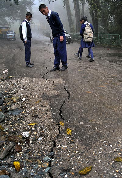 Schoolboys stop to look at a crack running down a road following an earthquake in Gangtok