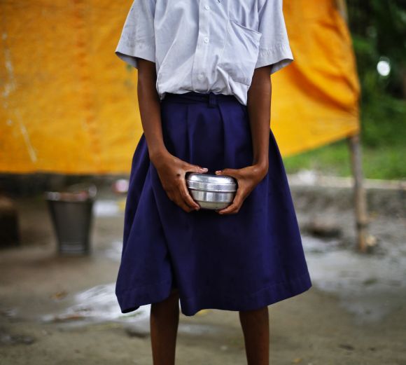 A school girl holds a container to receive her free mid-day meal at Brahimpur village in Bihar's Chapra district.