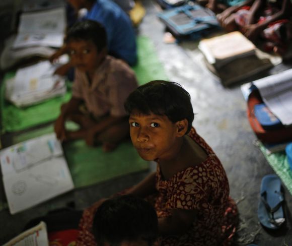 A school girl watches the camera while studying inside her classroom before having the free mid-day meal in Bihar