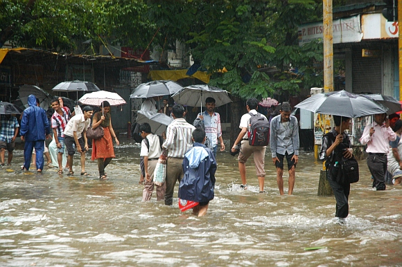 Commuters wade through a waterlogged road in central Mumbai