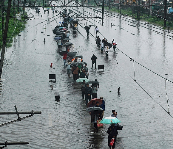 Commuters walk through the waterlogged railway tracks at the Kurla harbour line.