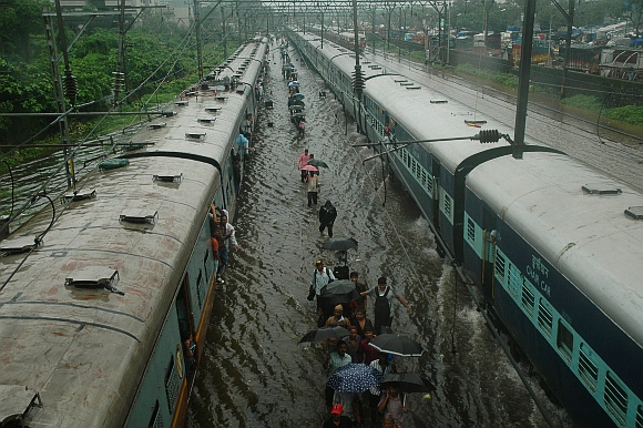Commuters walk through the waterlogged railway tracks at the Kurla harbour line.