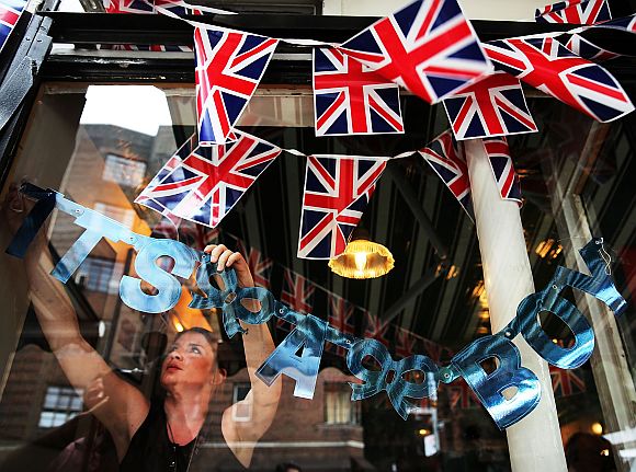 Hayley Simmonds, an employee at the British restaurant and grocery Tea & Sympathy, hangs a sign in the window celebrating the birth of Catherine, Duchess of Cambridge, and her husband Prince William's first child