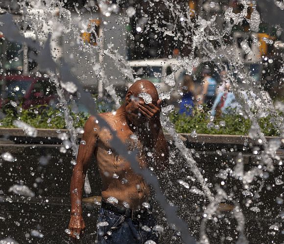 A man cools down at a fountain in Columbus Circle during a heat wave in Manhattan