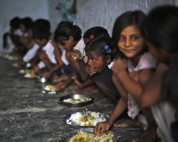 School children eat their free mid-day meal, distributed by a government-run primary school, at Brahimpur village in Chapra district, Bihar