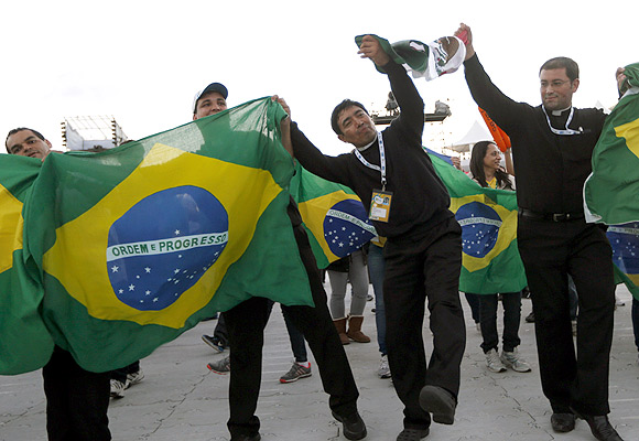 Priests dance with Brazilian flags before Pope Francis celebrates a mass at Copacabana Beach.