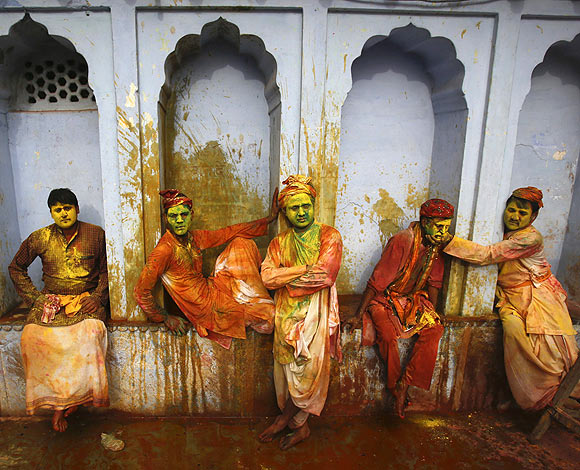 Hindu devotees covered in coloured water and powder sit in a temple during Lathmar Holi at the village of Nandgaon in Uttar Pradesh