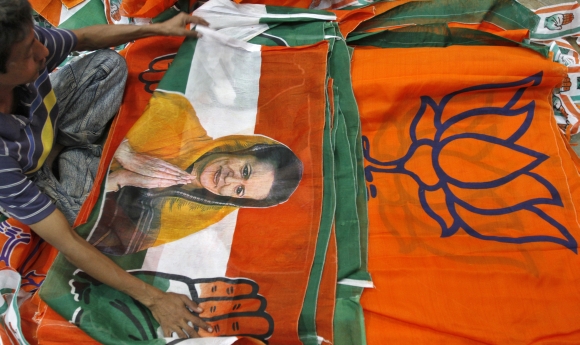 A worker looks at a Congress party flag carrying a picture of its party chief Sonia Gandhi next to flags of BJP