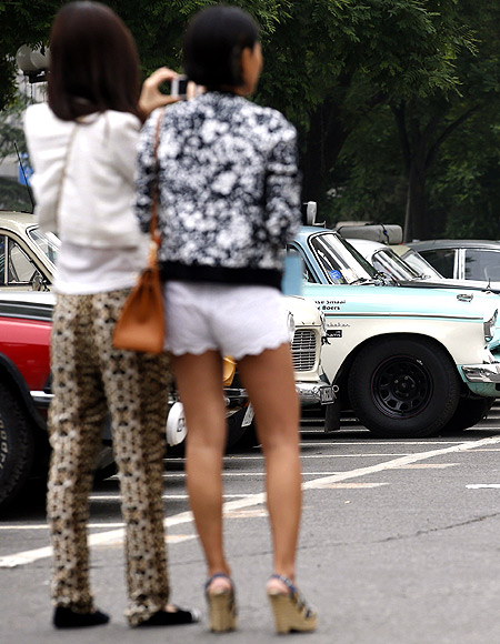 Women look around classic cars participating in the Peking-to-Paris Motor Challenge in Beijing