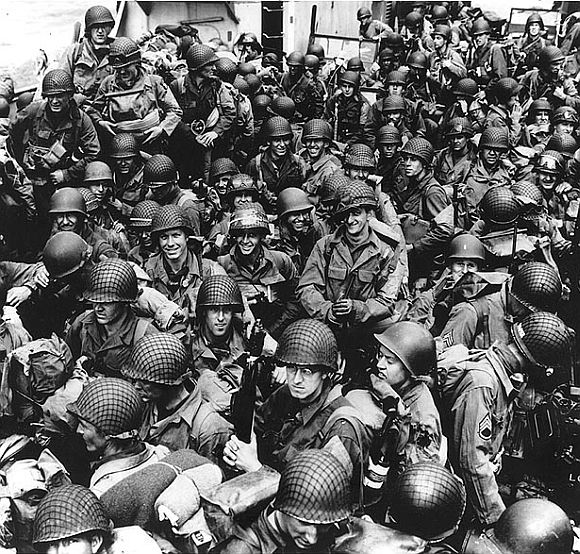 Army troops on board a LCT, ready to ride across the English Channel to France. Some of these men wear 101st Airborne Division insignia