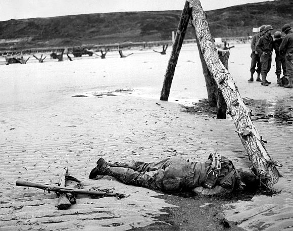 Crossed rifles in the sand are a comrade's tribute to this American soldier who sprang ashore from a landing barge and died at the barricades of Western Europe in this 1944 file photo