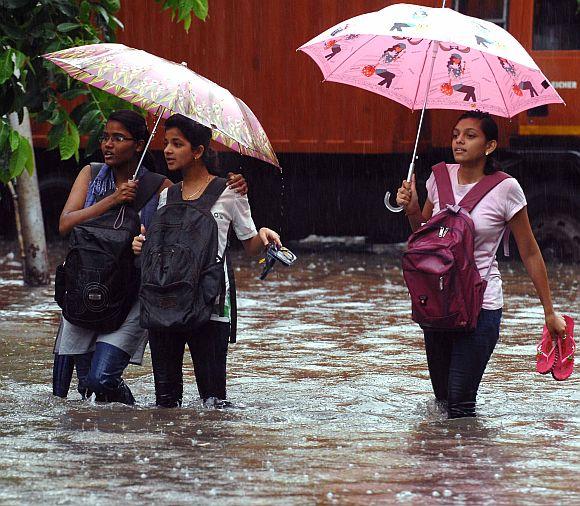 A group of girls wade through a waterlogged street in Parel locality.