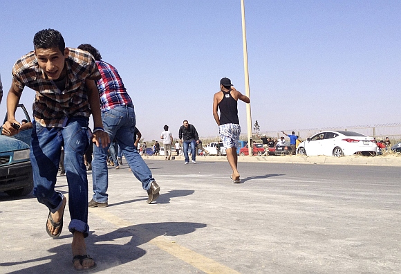 Protesters run for cover during an attack on a Libyan militia, the Libya Shield brigade, headquarters in Benghazi