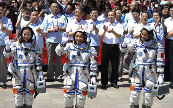 Chinese astronauts (from L to R) Wang Yaping, Zhang Xiaoguang and Nie Haisheng wave before leaving for the Shenzhou-10 mission.
