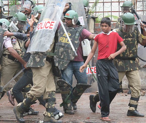 Police personnel take away detained protestors