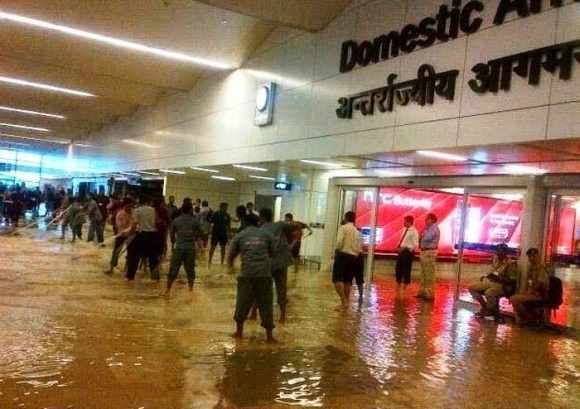 Staff at the Delhi airport try to clear the water from the domestic terminal