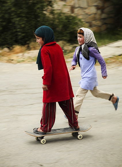 An orphan Afghan girl skateboards in Kabul as her friend tries to catch up