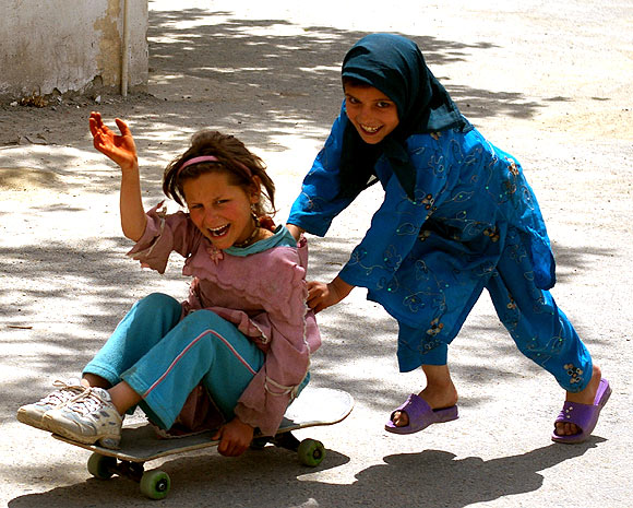 Two girls from the Kufa Orphange in Kabul play around with the skateboard