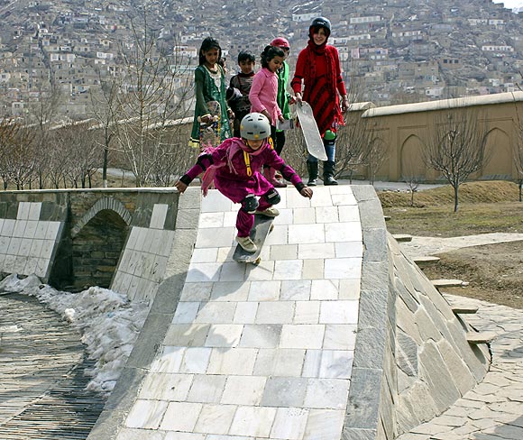 A girl slides down the skating ramp in a garden in Kabul as her friends watch in awe