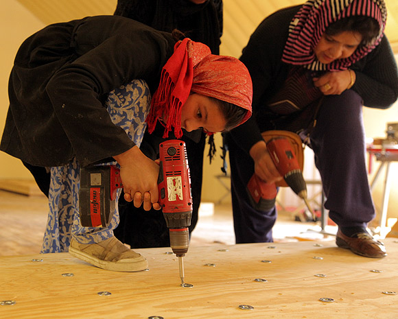 Students and teachers drill a skateboard at the facility in Kabul. Volunteers, students and teachers make the boards themselves, cutting off the edges and then sanding it