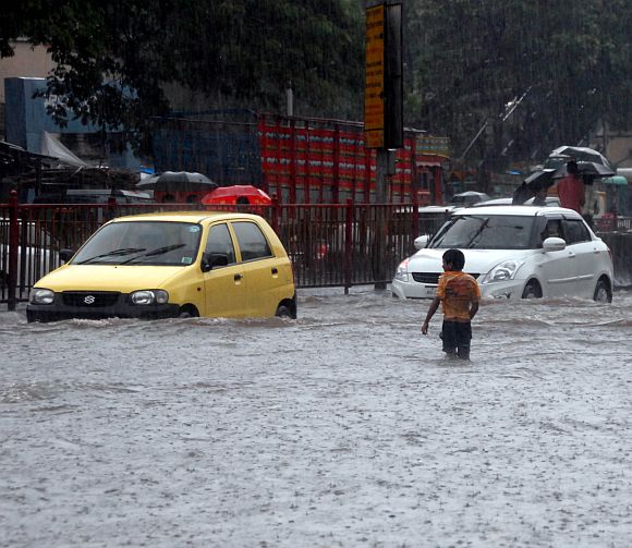 A boy tries to cross a flooded road in Parel