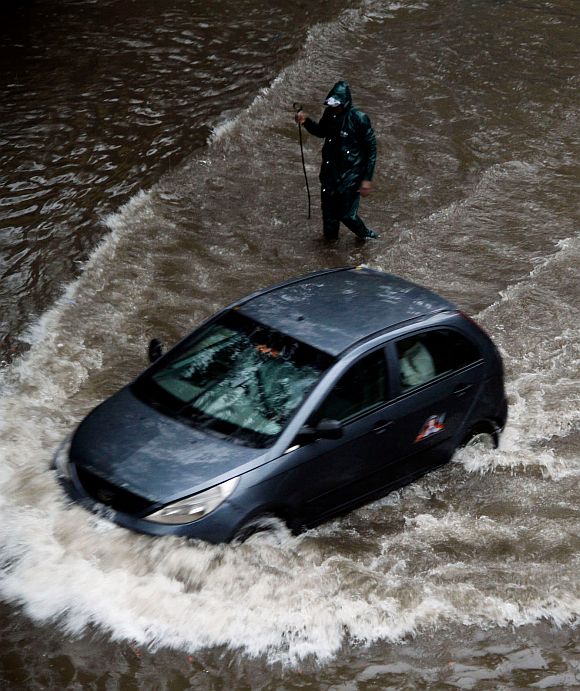 A car makes its way through a flooded street in Andheri